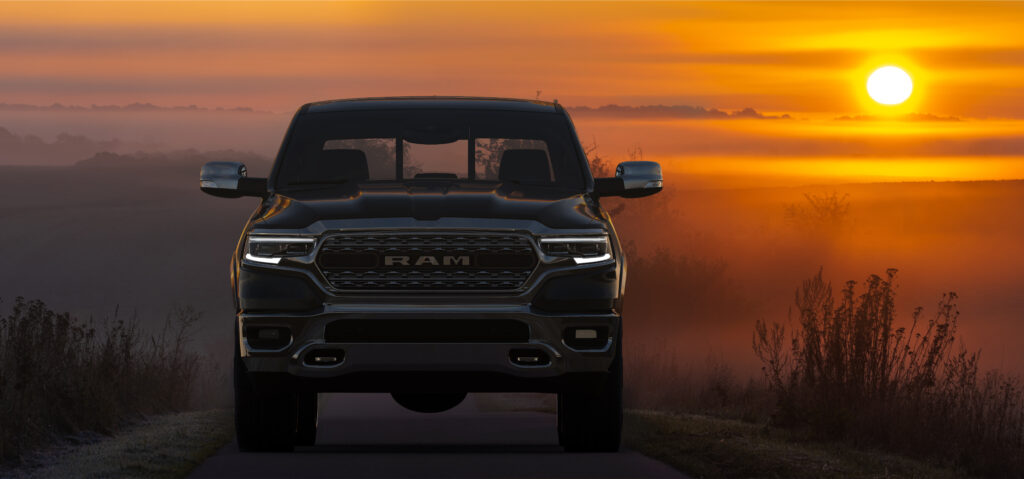 black Ram truck driving down a road with a sunset in the background