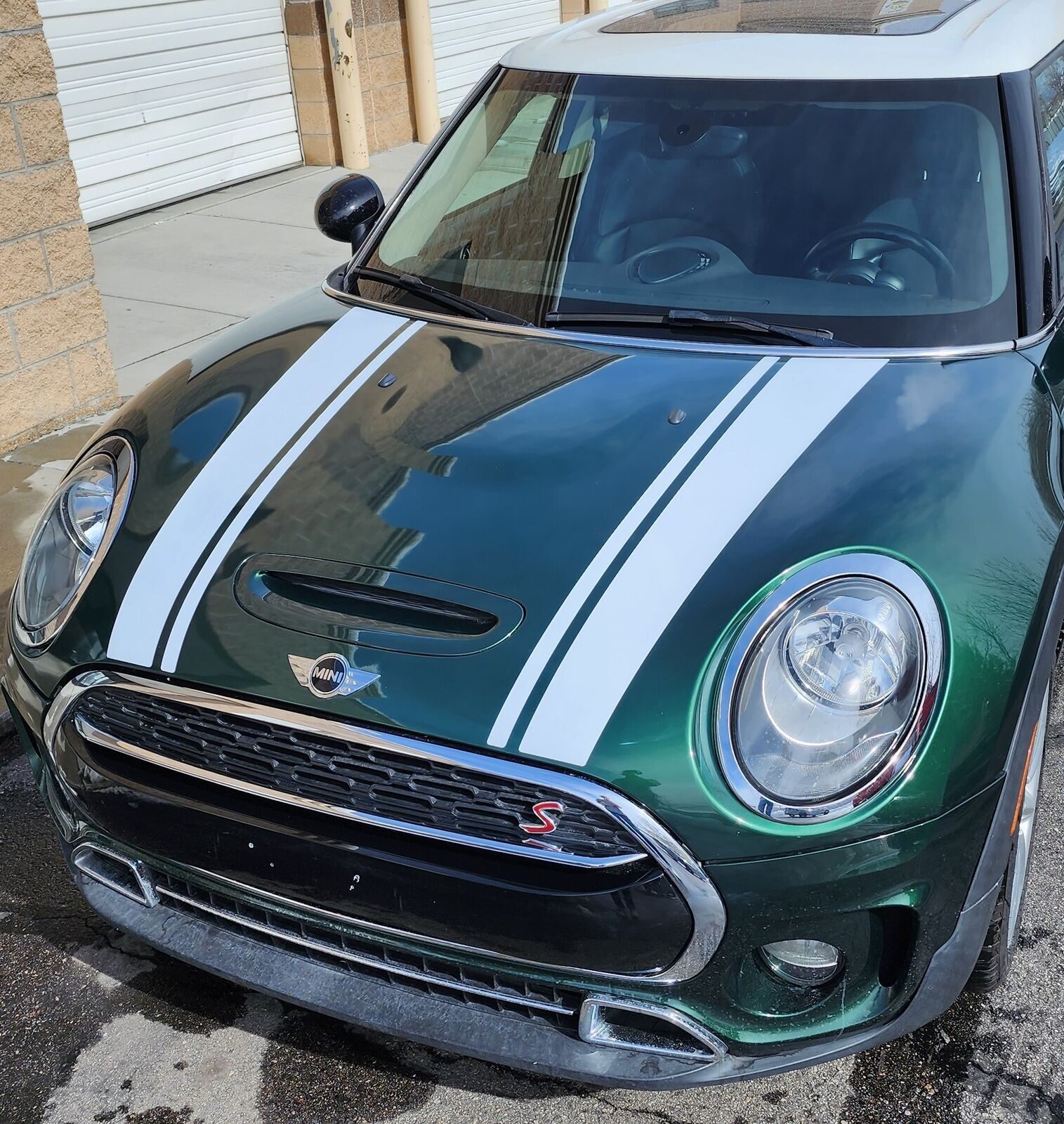 green mini cooper with white racing stripes on hood