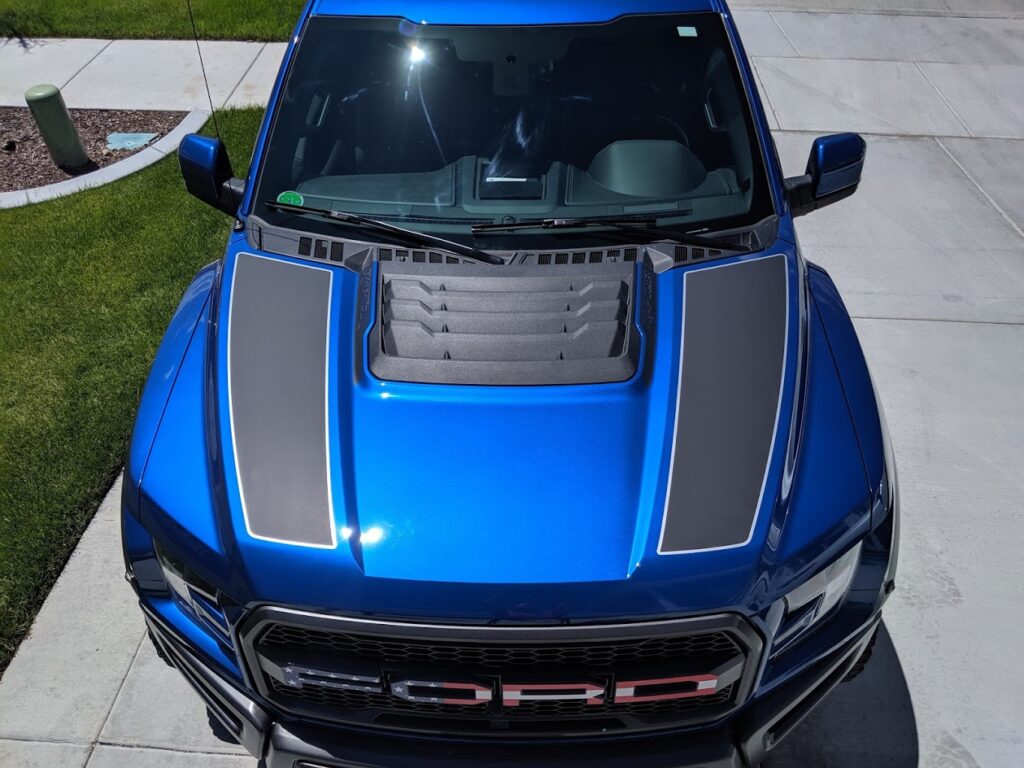 blue Ford truck with custom black stripes on hood and American flag in Ford logo